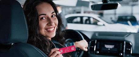 Motorista sorrindo dentro do carro segurando a tag Sem Parar